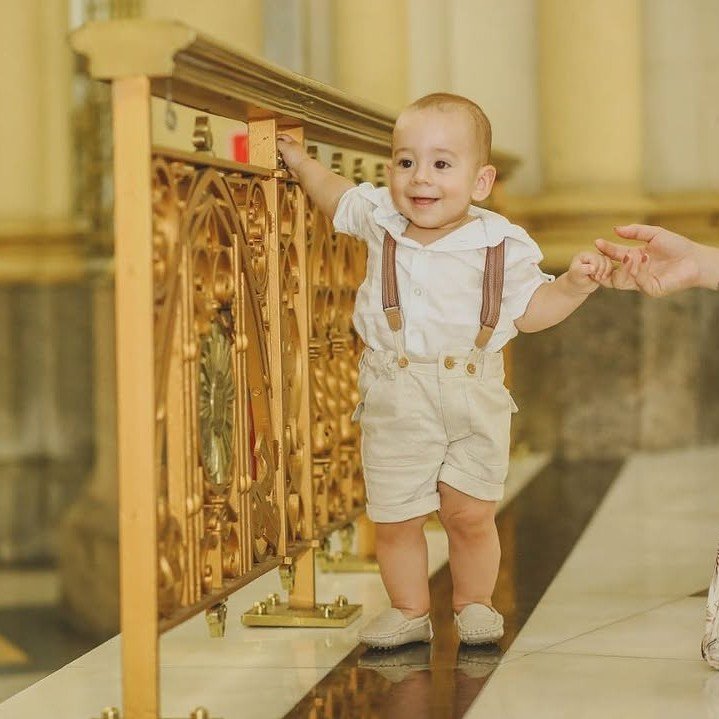 Bebê sorridente segurando a grade do altar durante o batismo, na igreja