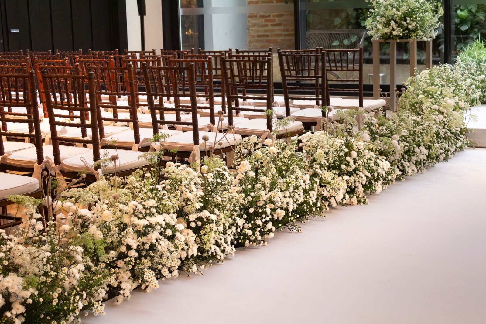 Corredor de cerimônia decorado com flores brancas e cadeiras